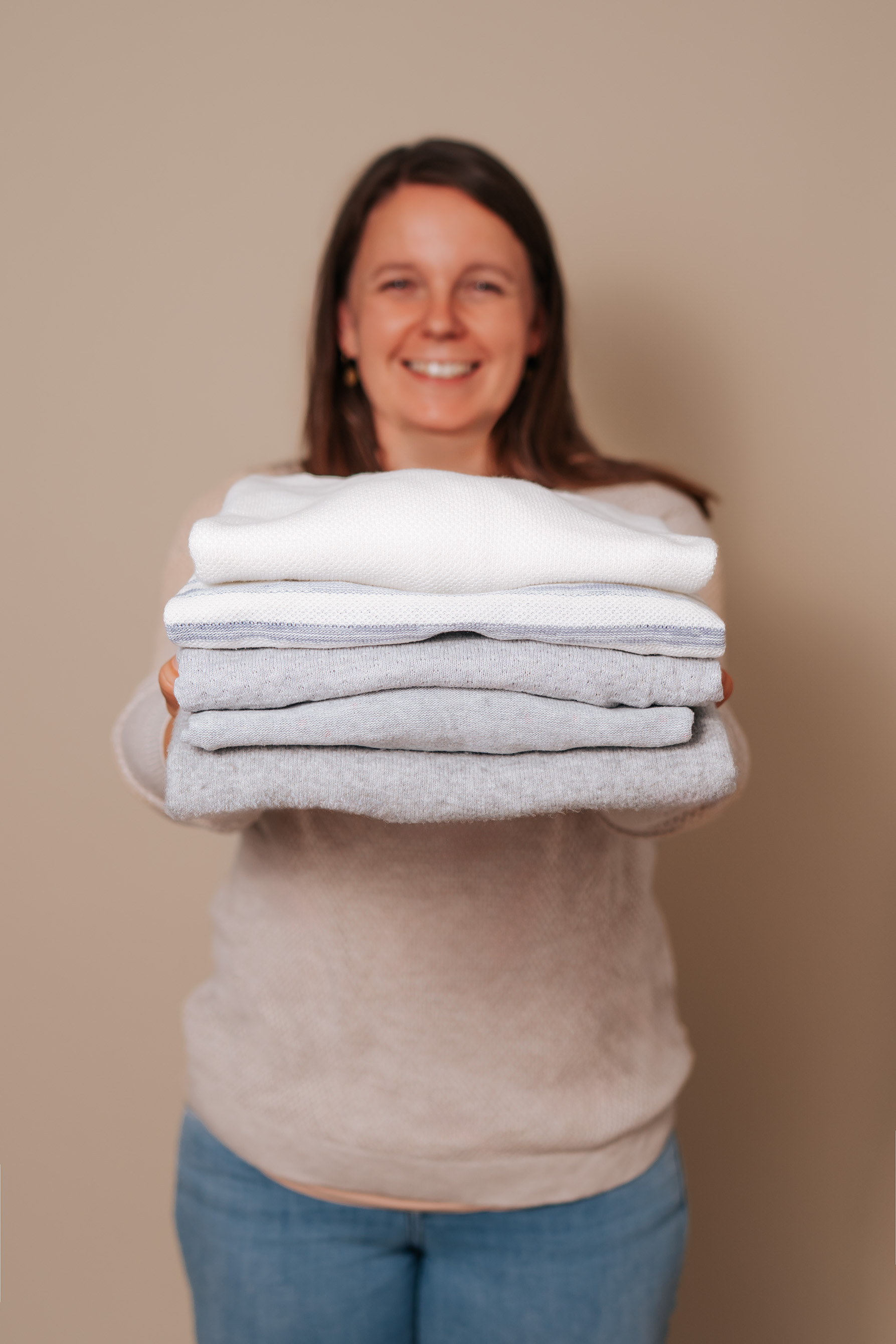 title Eine junge Frau hält ein Stück möRKISIG WeiS / GraUM Beig AND ergnet WOLLEN SchtÜCKe In Den HAnD.